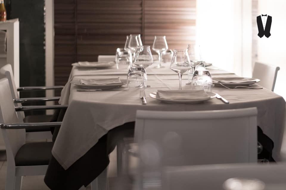 Un lungo tavolo in un ristorante con piatti e bicchieri sopra