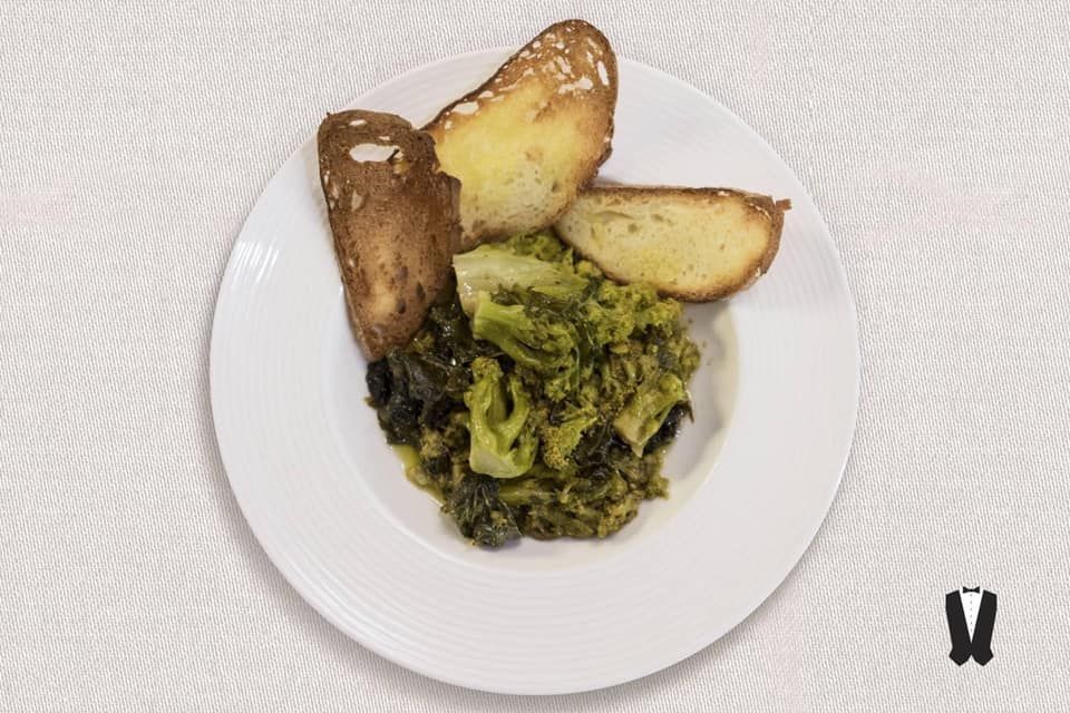 Un piatto bianco condito con broccoli, patate e pane all'aglio.