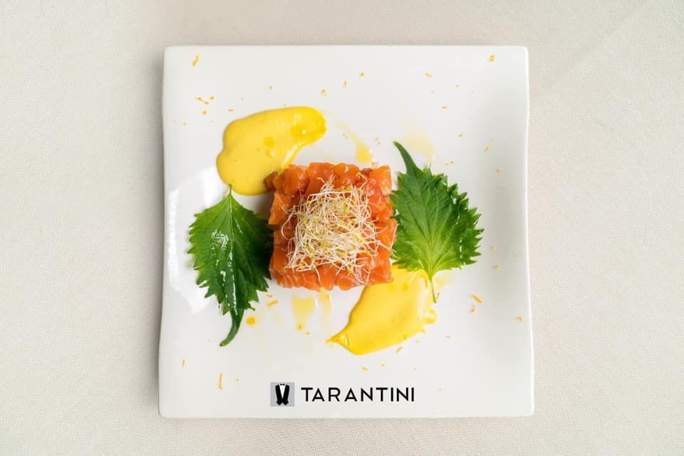 Un piatto bianco sormontato da un pezzo di cibo e salsa.