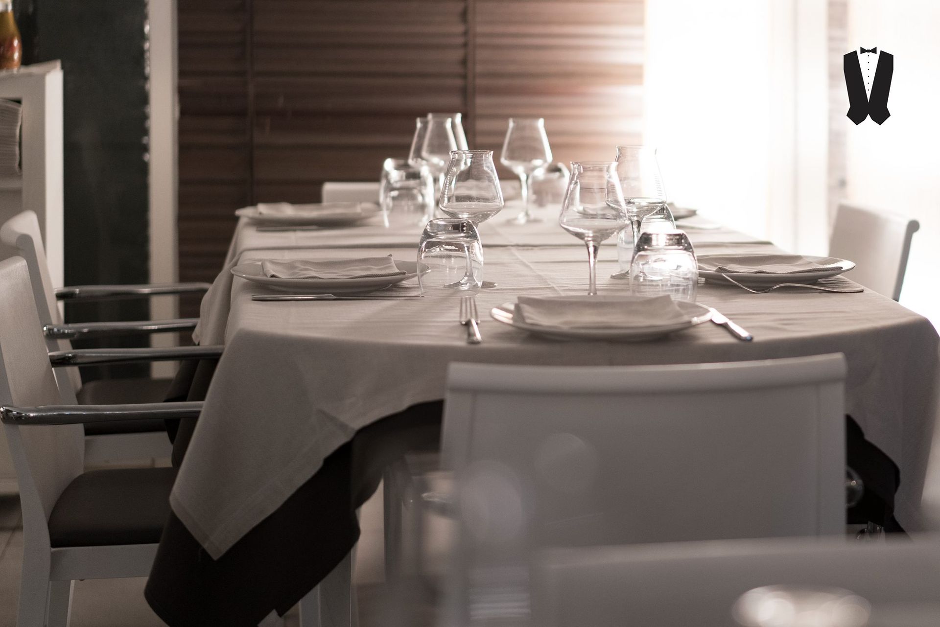 Un lungo tavolo con piatti e bicchieri in un ristorante.