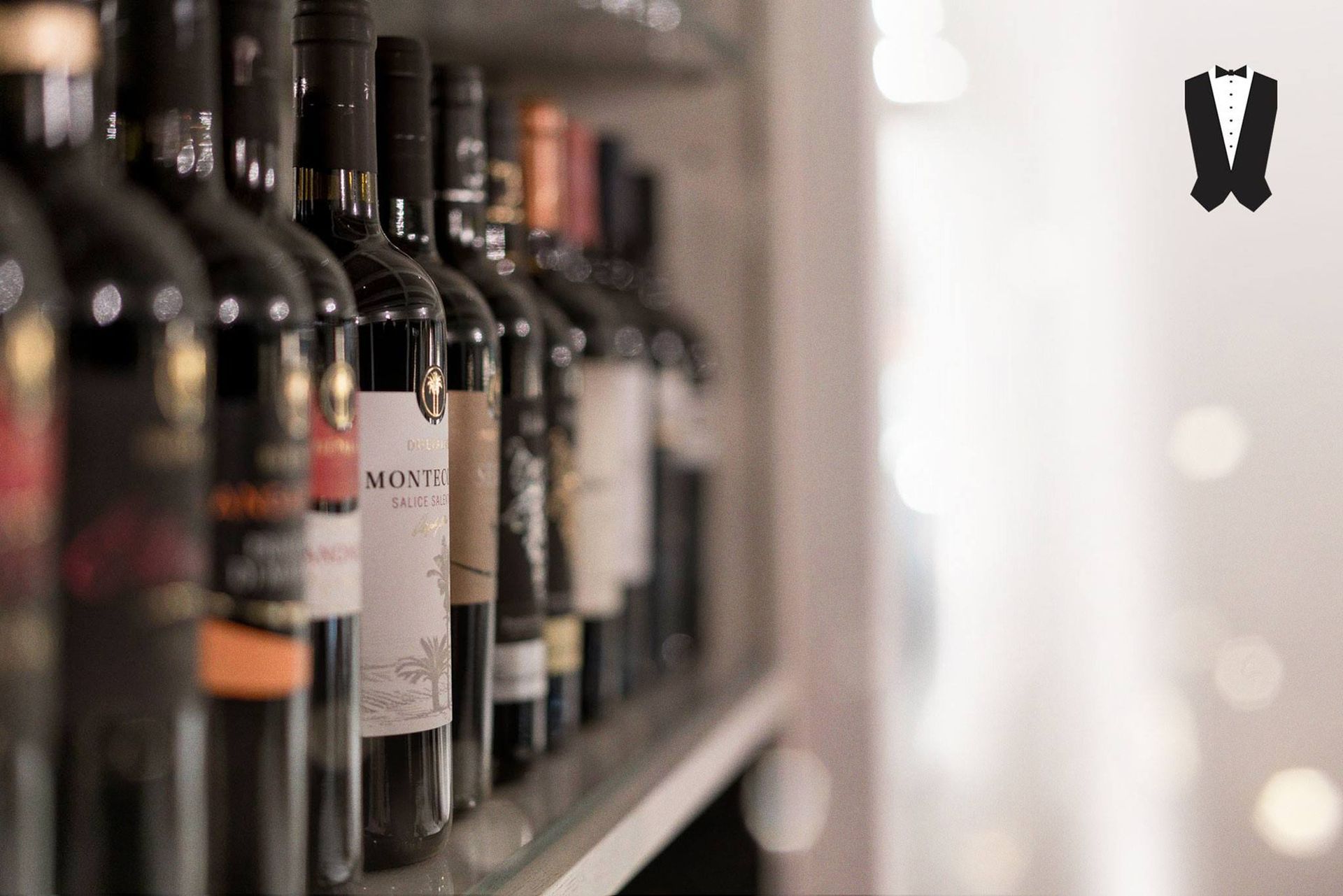 Su uno scaffale sono allineate una fila di bottiglie di vino.