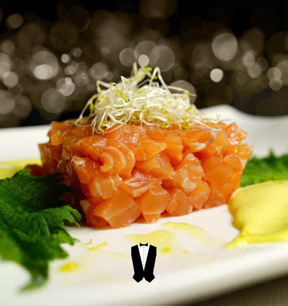 Un piatto bianco condito con un pezzo di salmone e una salsa gialla.