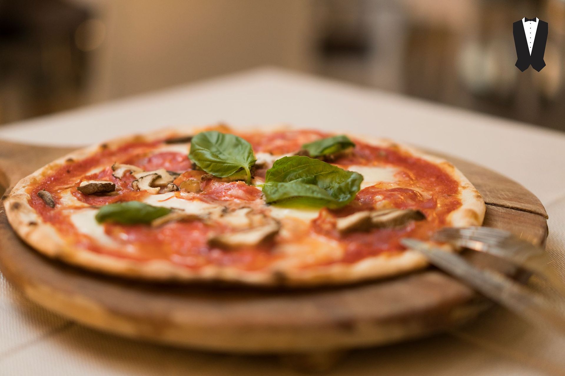 Una pizza è seduta su un tagliere di legno su un tavolo.