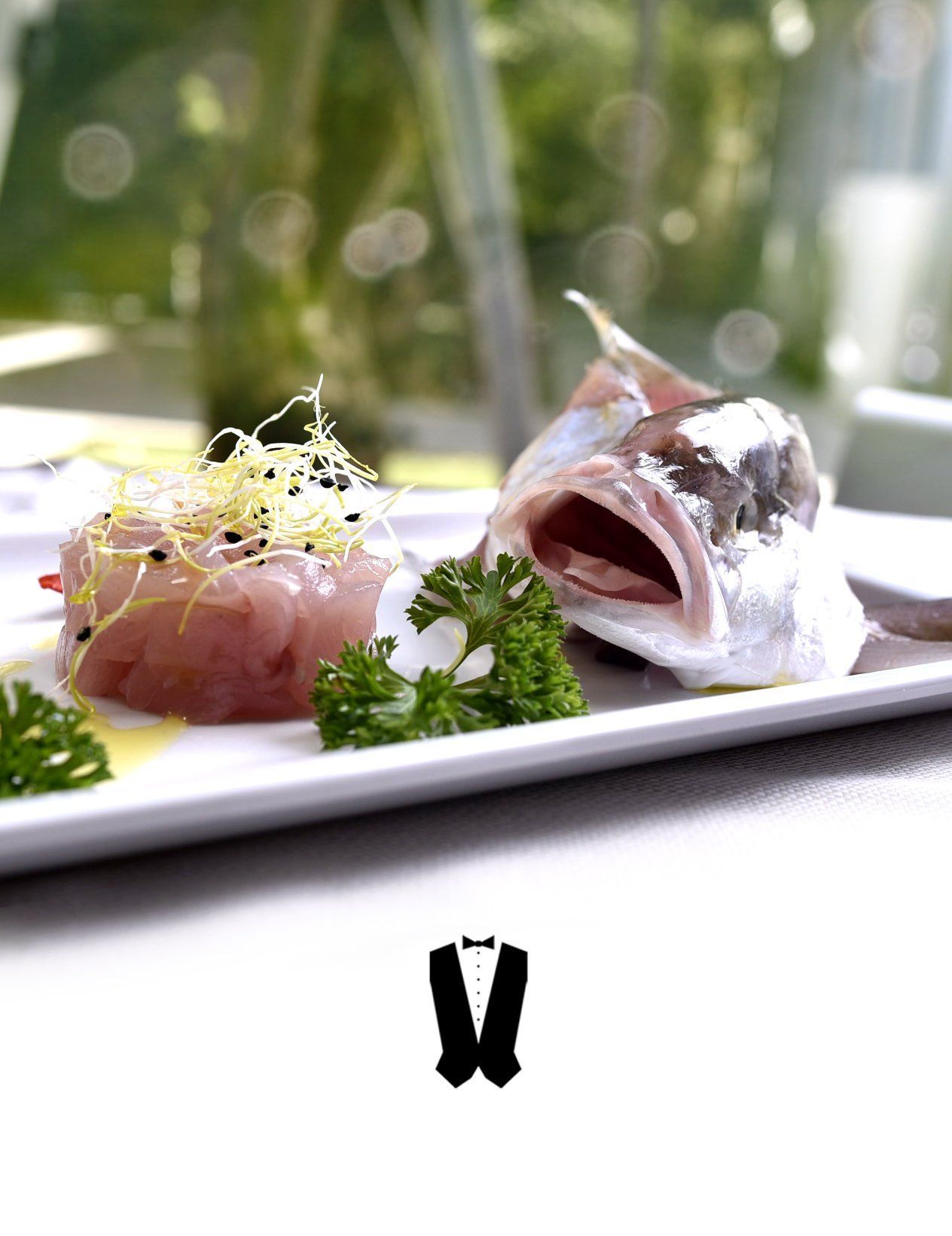 Un piatto bianco condito con pesce e prezzemolo su un tavolo.