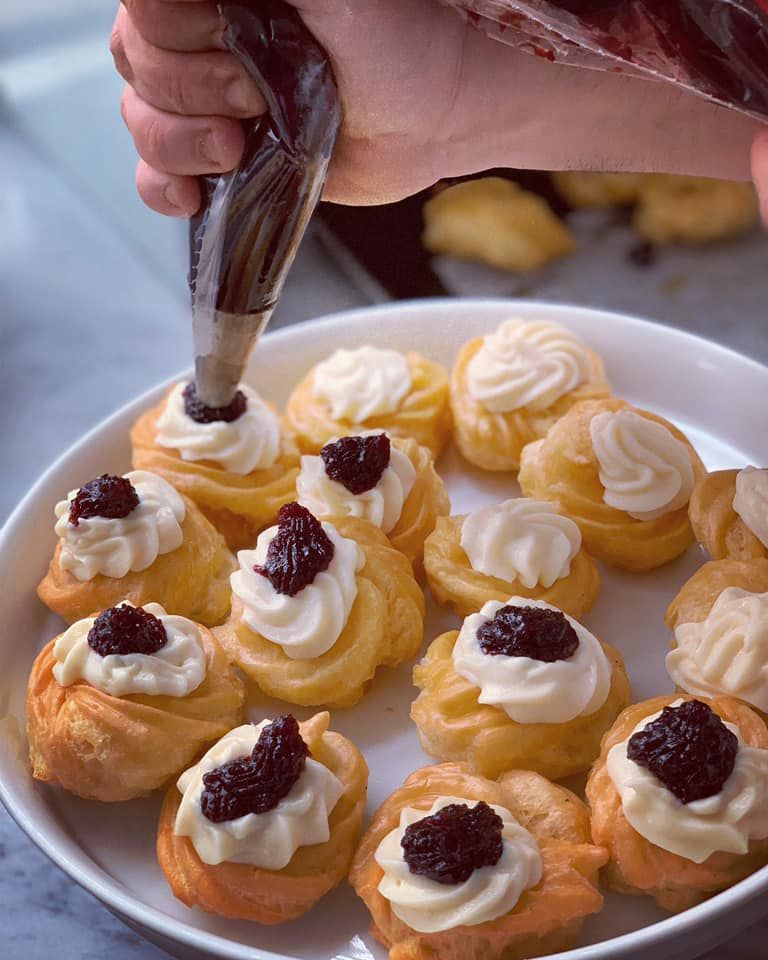 Una persona sta versando la glassa su un piatto di pasticcini.