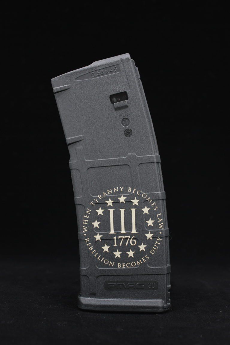 A gray magazine with 1776 on it is sitting on a black surface.