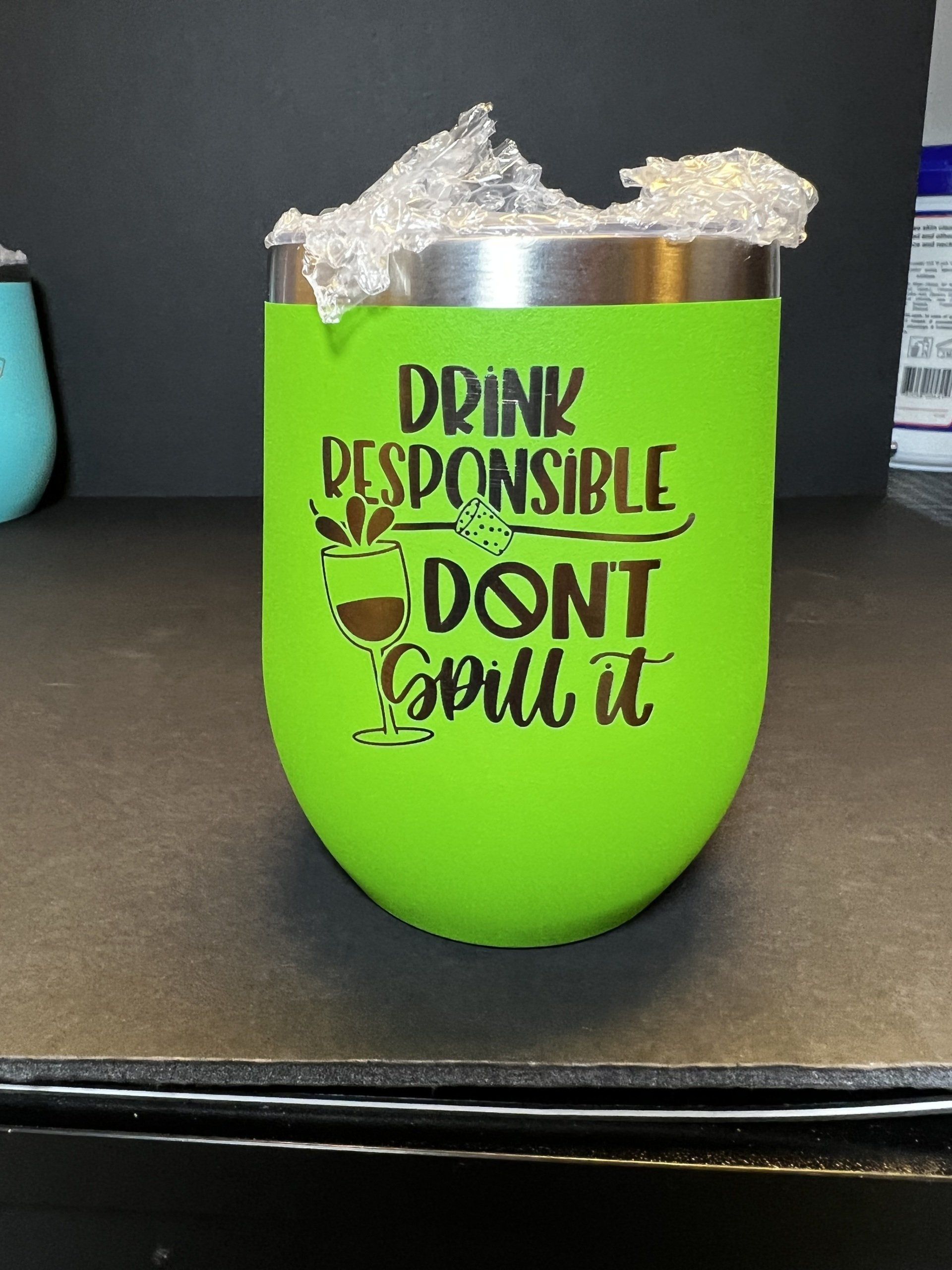A green tumbler that says drink responsible do n't spill it