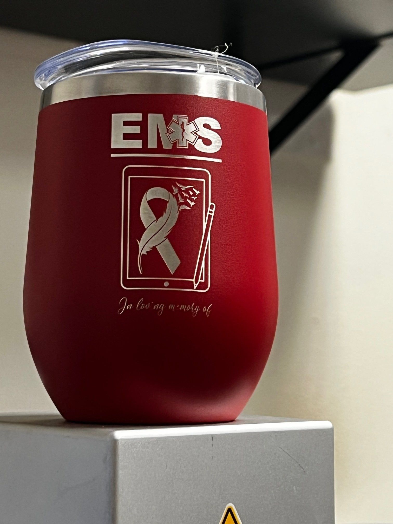 A red tumbler with the word ems on it