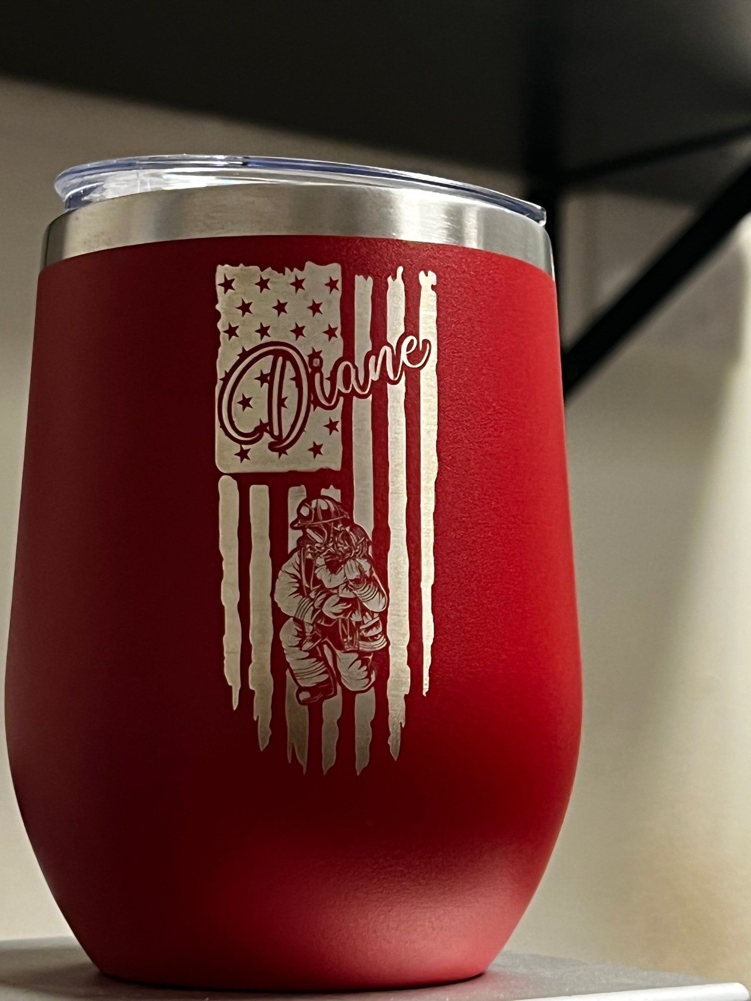 A red wine tumbler with a fireman and an american flag on it.