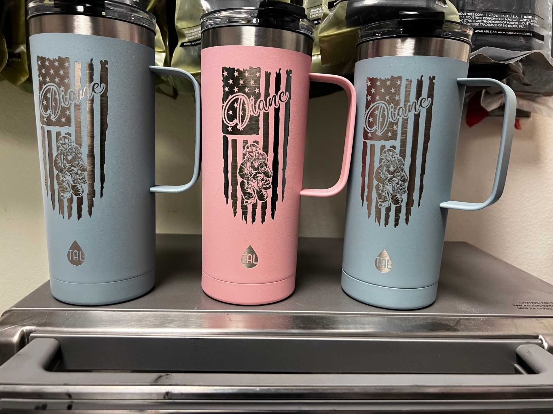 Three mugs with american flags on them are sitting on a shelf.