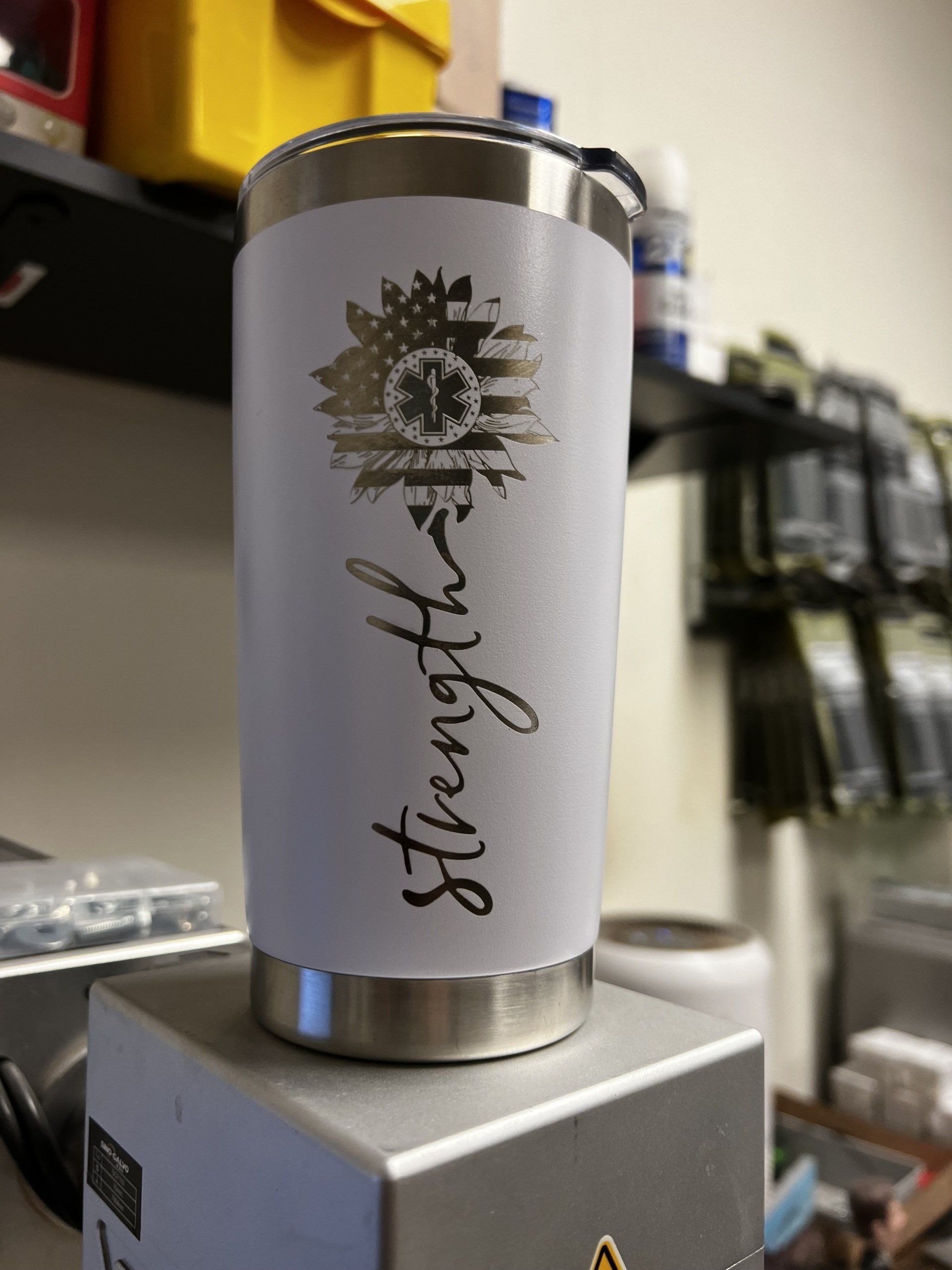 A white tumbler with the word strength on it