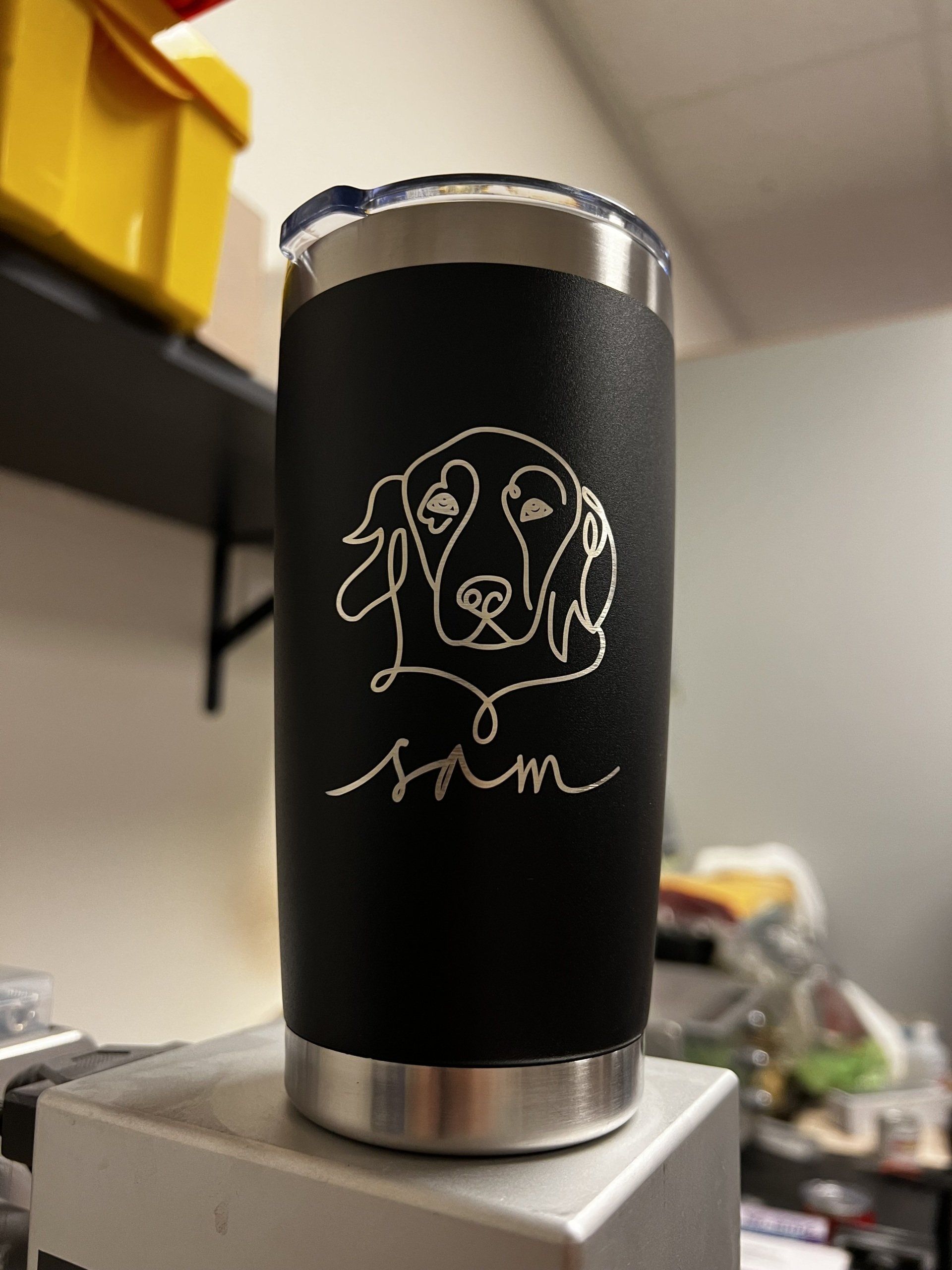 A black tumbler with a drawing of a dog on it