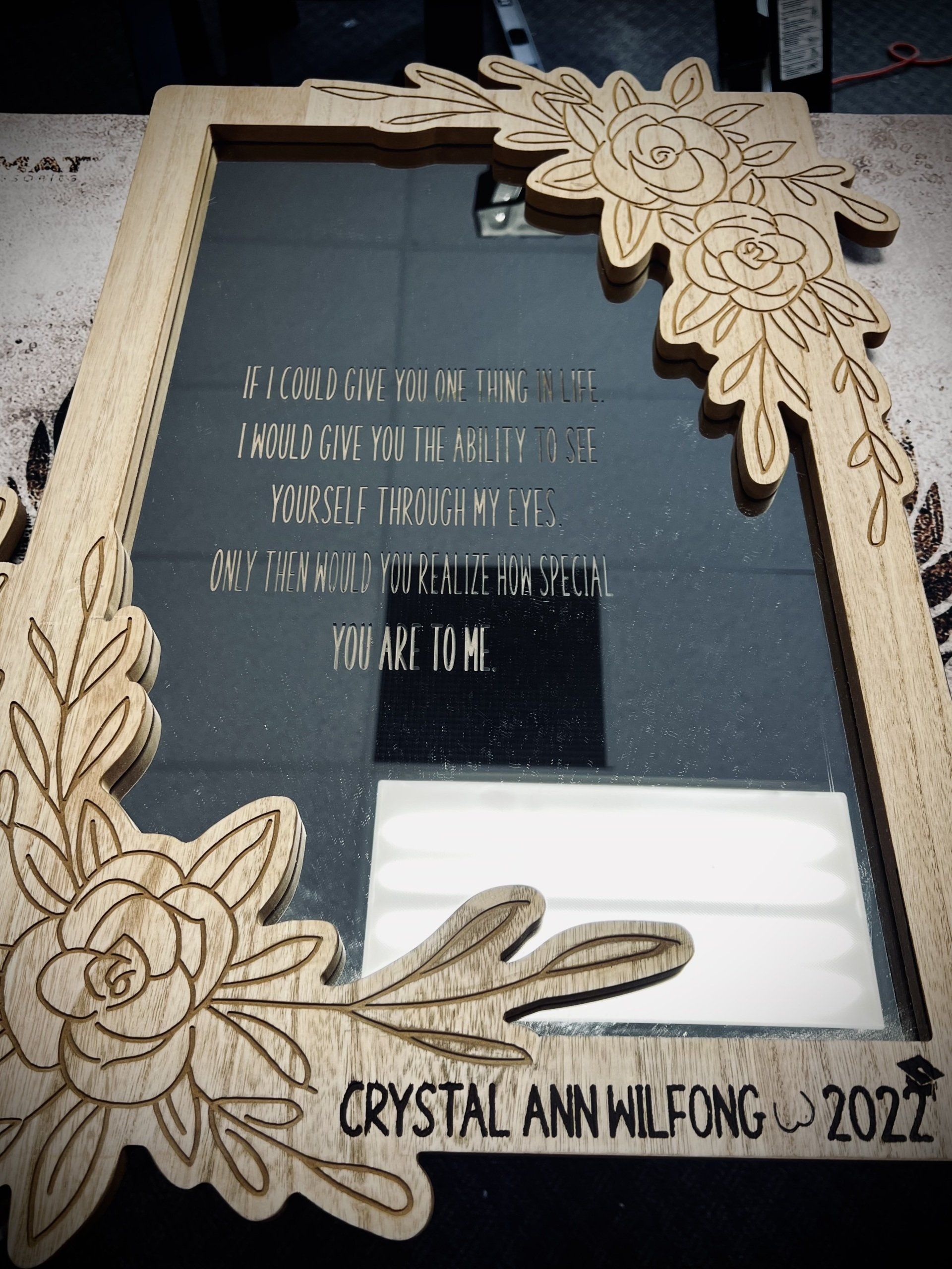 A wooden picture frame with flowers and leaves on it