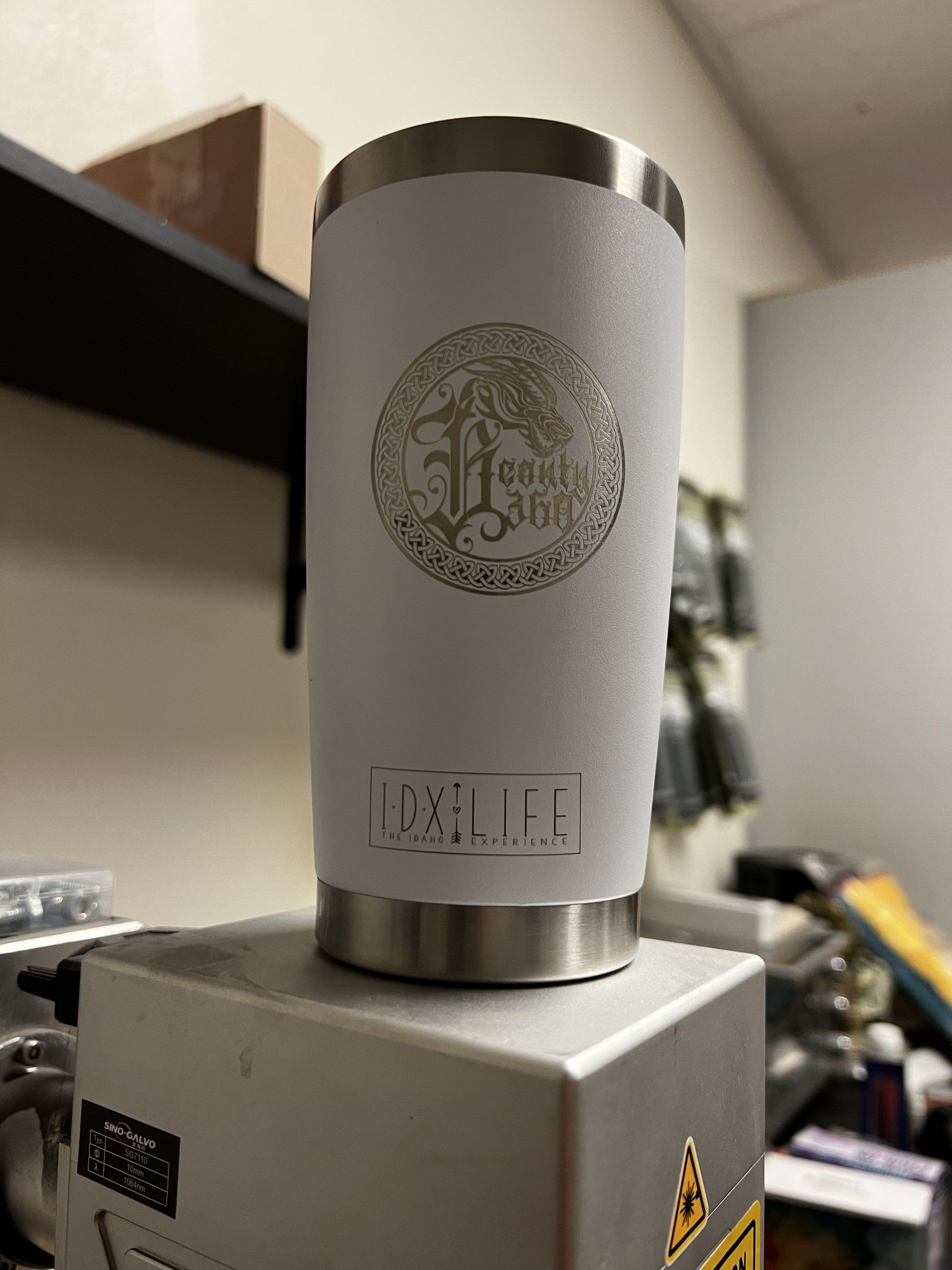 A white tumbler is sitting on top of a machine in a room.