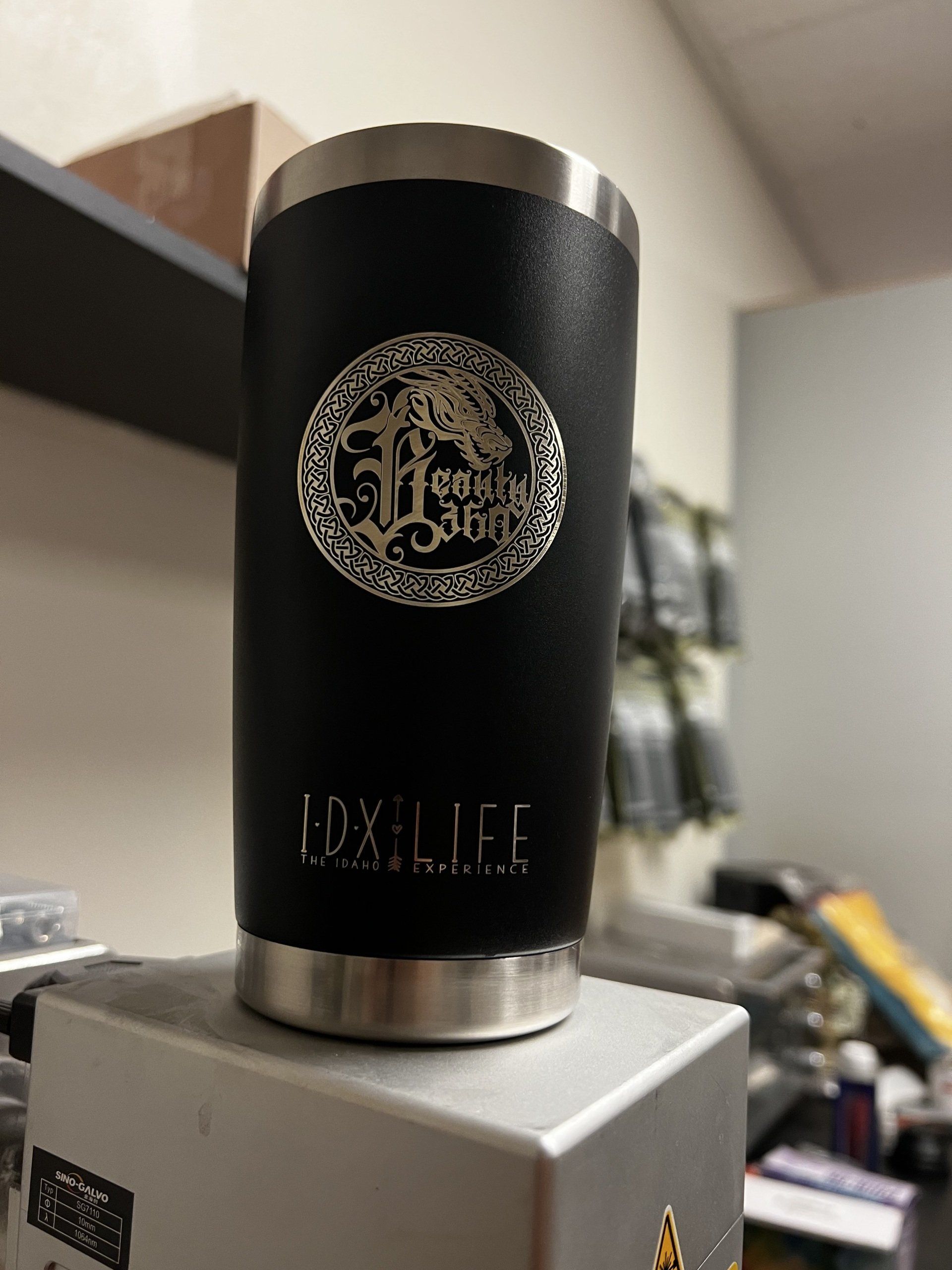 A black tumbler is sitting on top of a silver box.