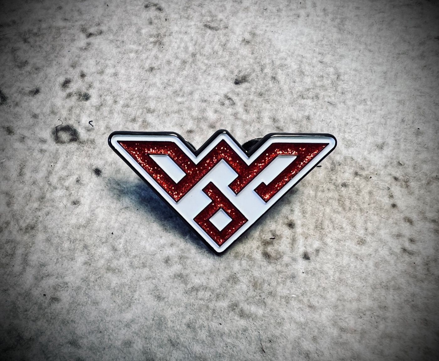 A red and white pin with the letter d on it