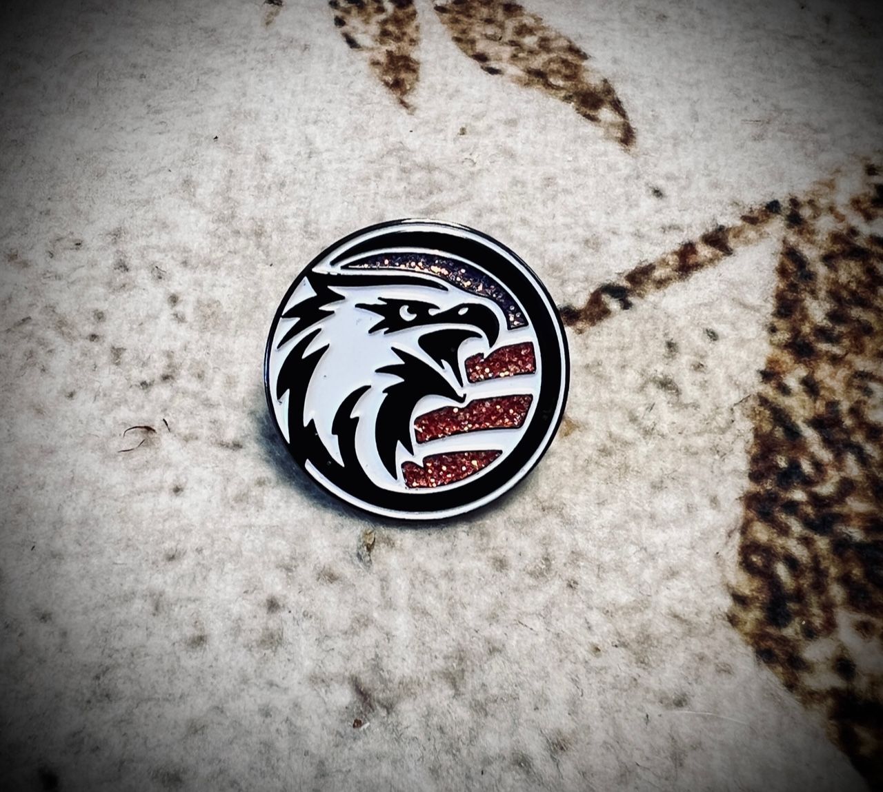 A black and white pin with an eagle on it