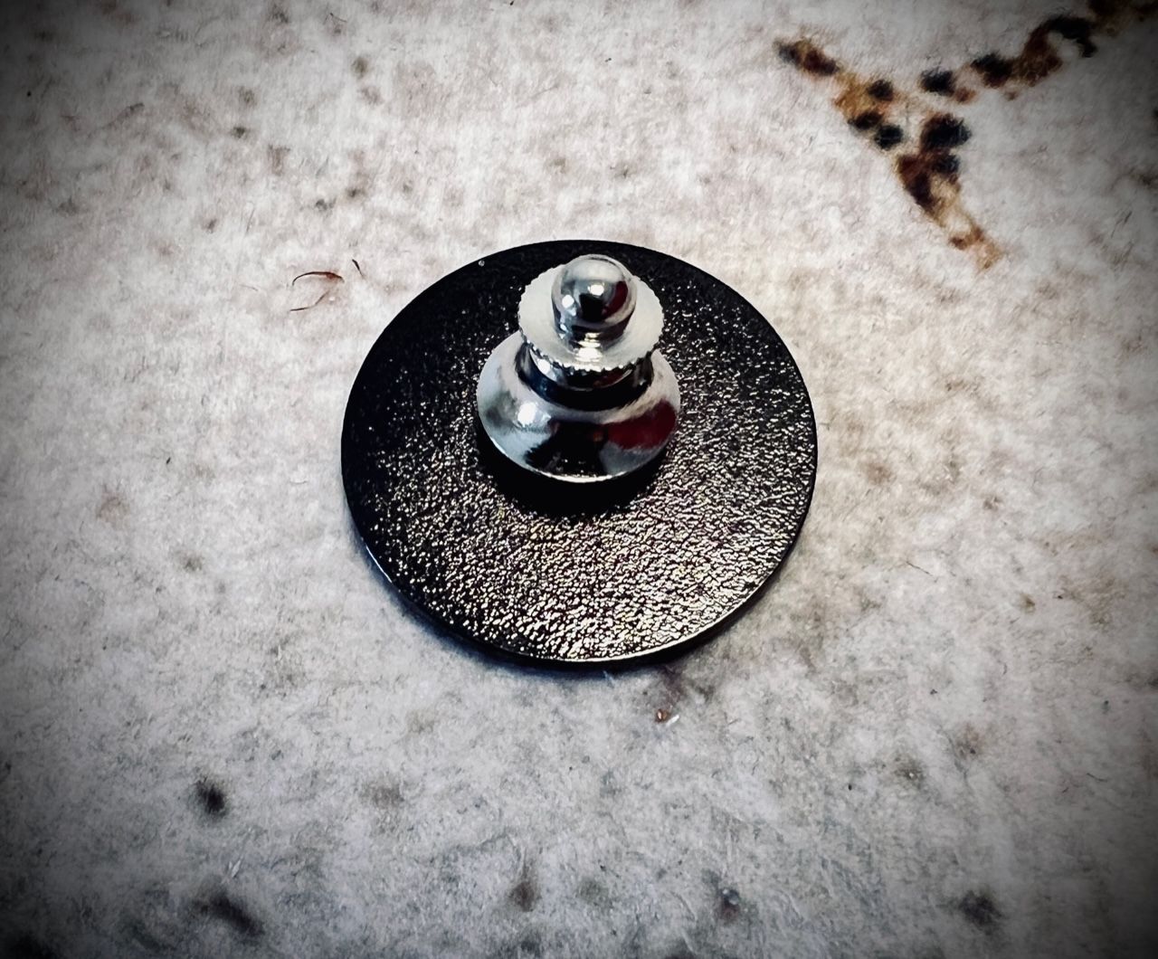 A black button with a silver screw on it