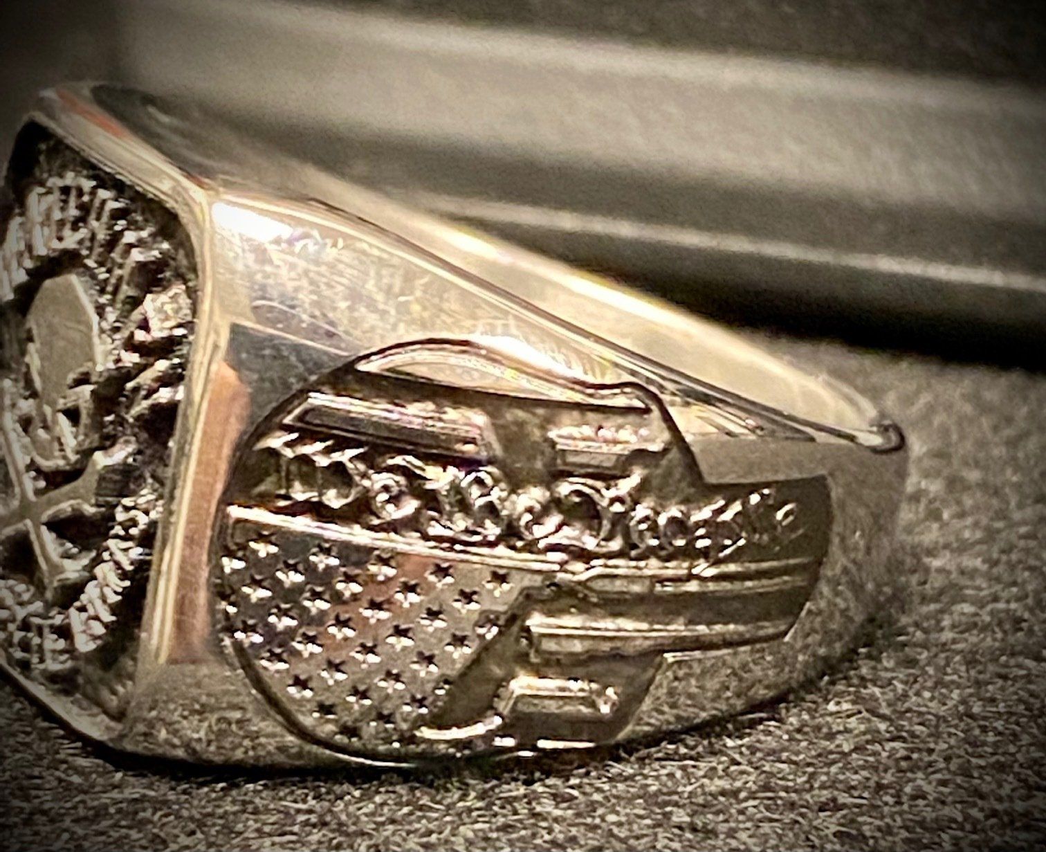 A close up of a silver ring with a skull and an american flag on it.