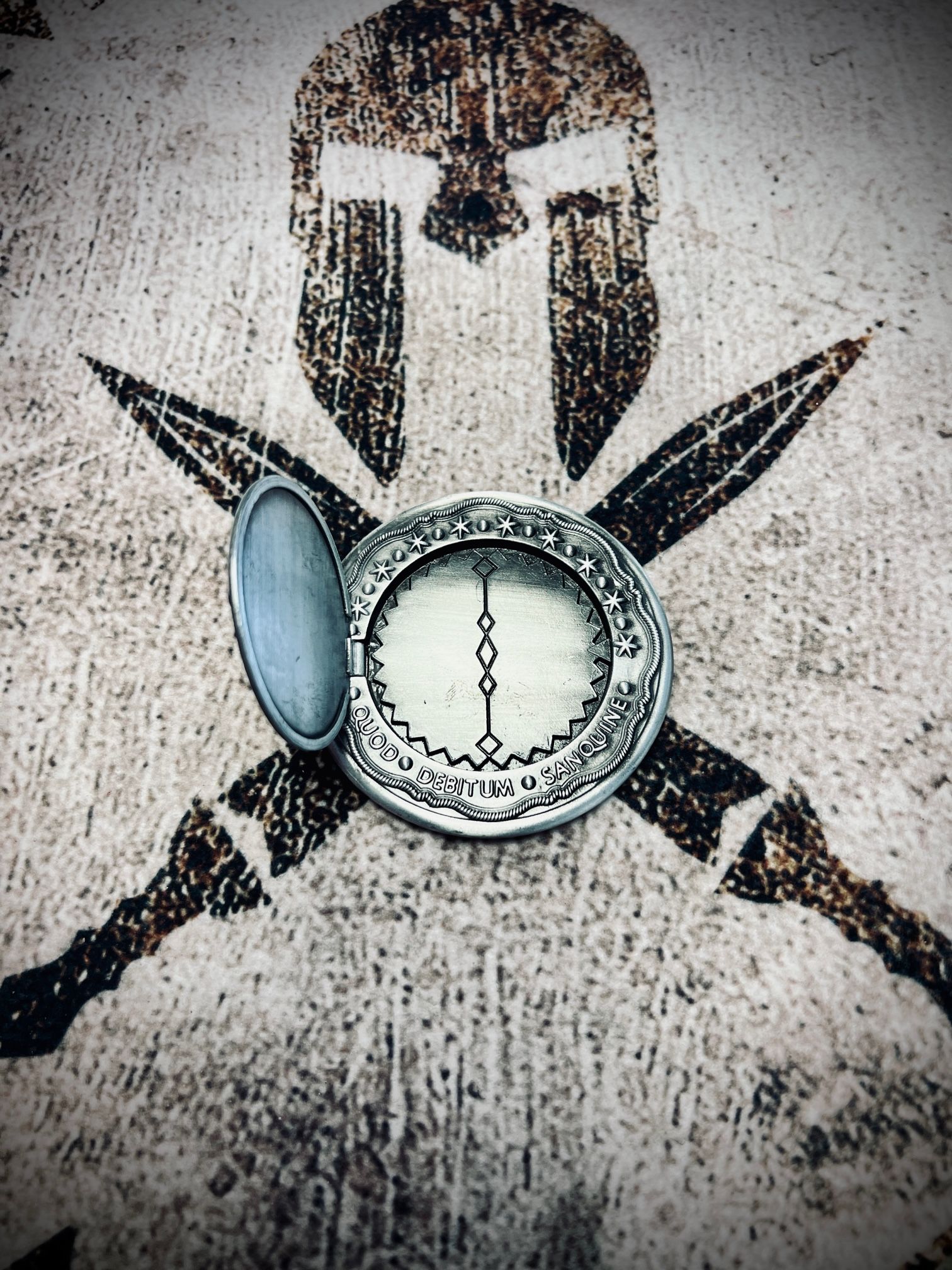 A compass is sitting on a table in front of a spartan helmet and crossed swords.