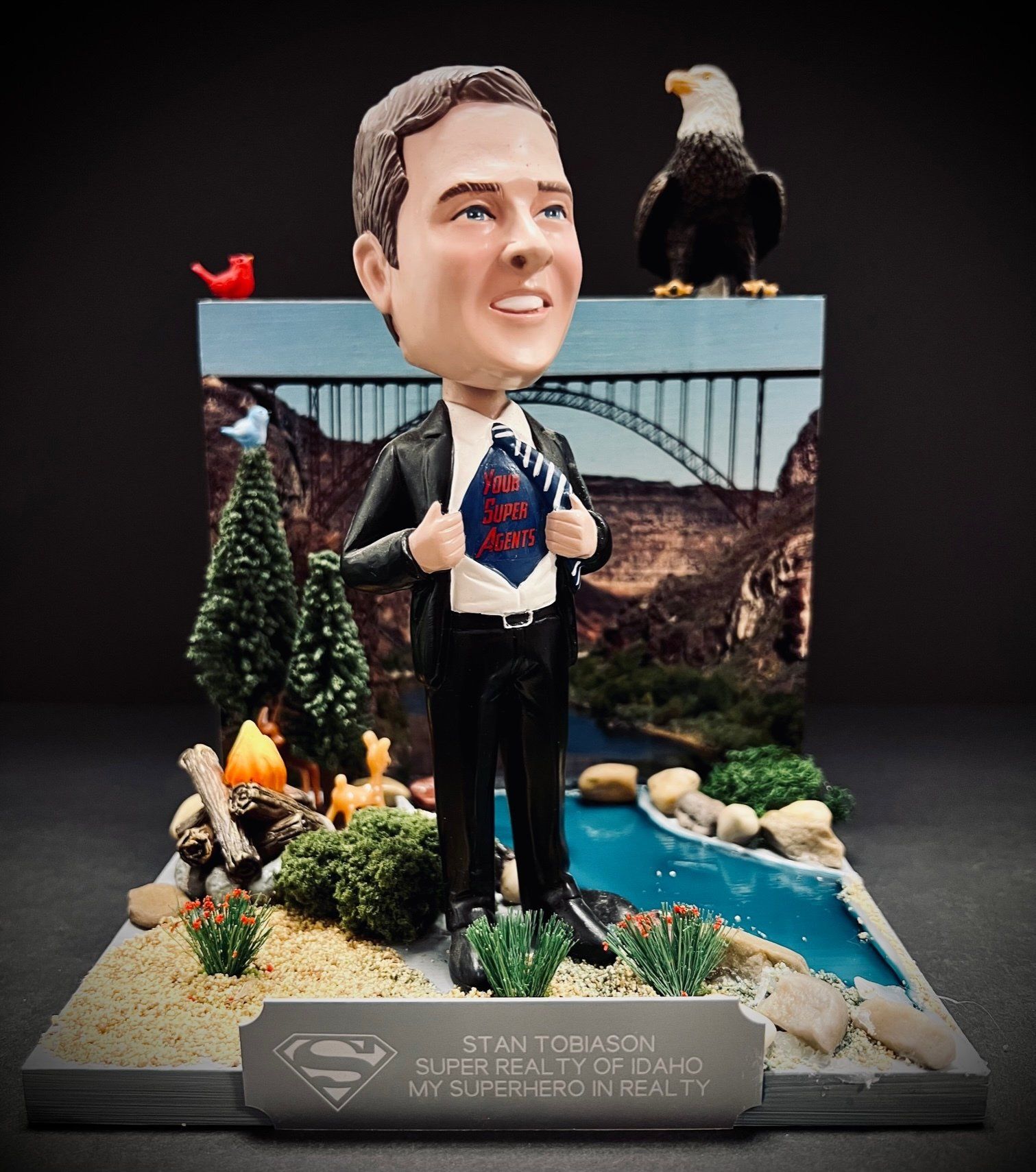 A bobble head of a man with a superman shirt on