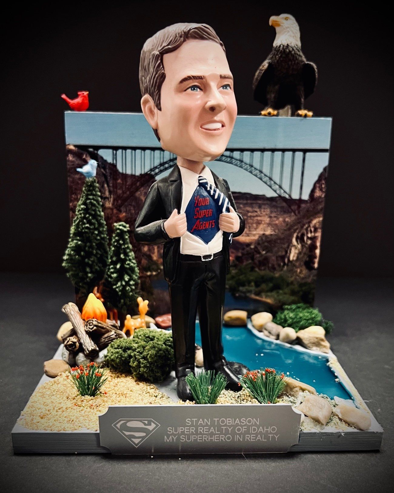 A bobble head of a man with a superman shirt on