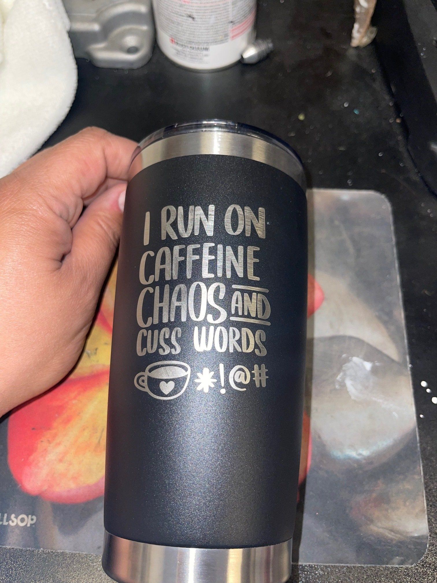 A person is holding a tumbler that says `` i run on caffeine , chaos and cuss words ''.