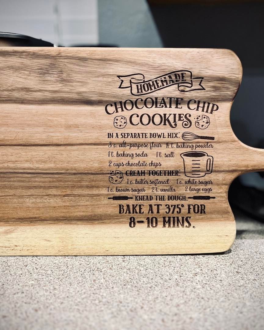 A wooden cutting board with a recipe for chocolate chip cookies on it.