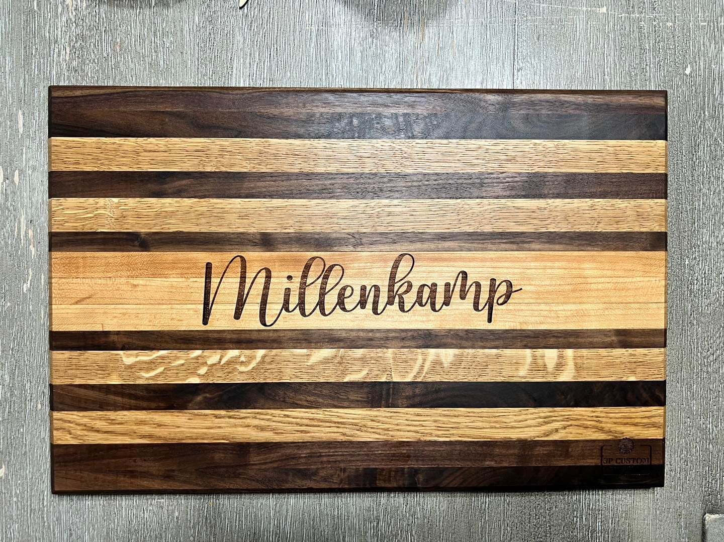 A wooden cutting board with the name millenkamp engraved on it.