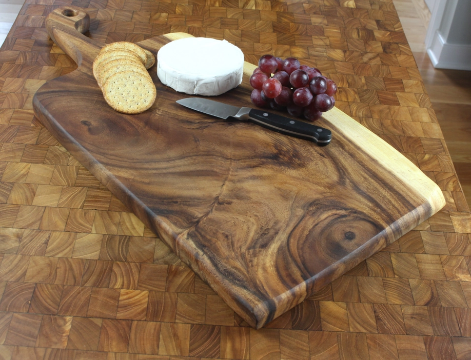 A wooden cutting board with crackers cheese and grapes on it