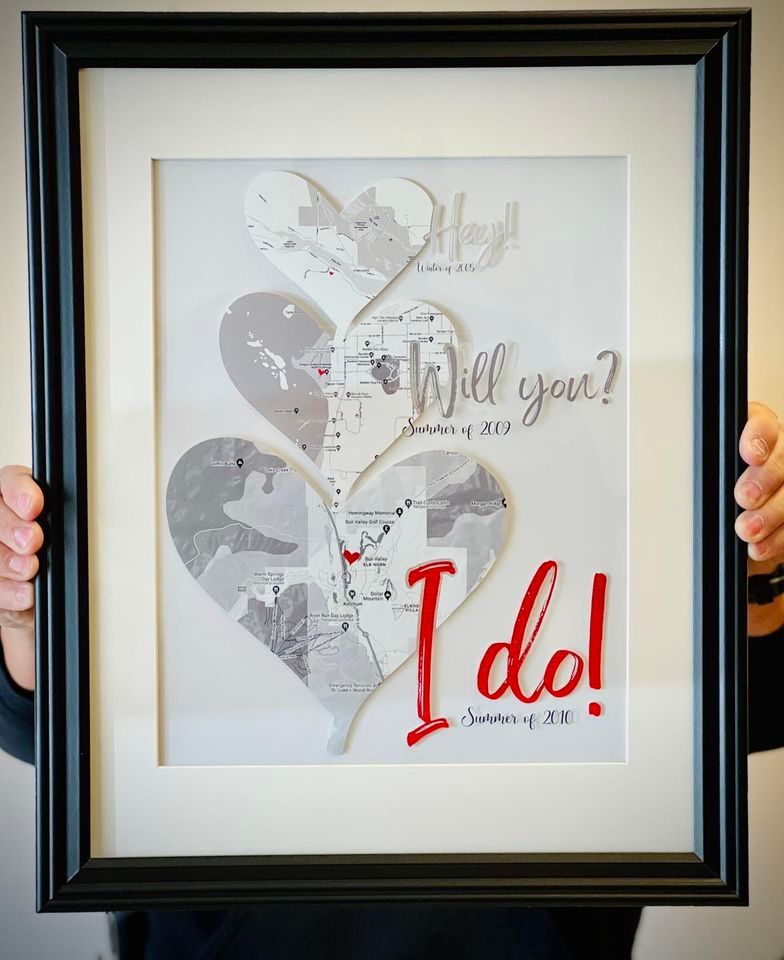 A person is holding a framed picture that says i do