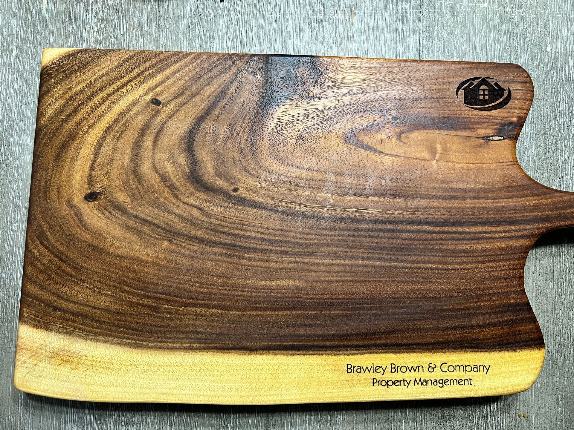 A wooden cutting board with a handle is sitting on a table.