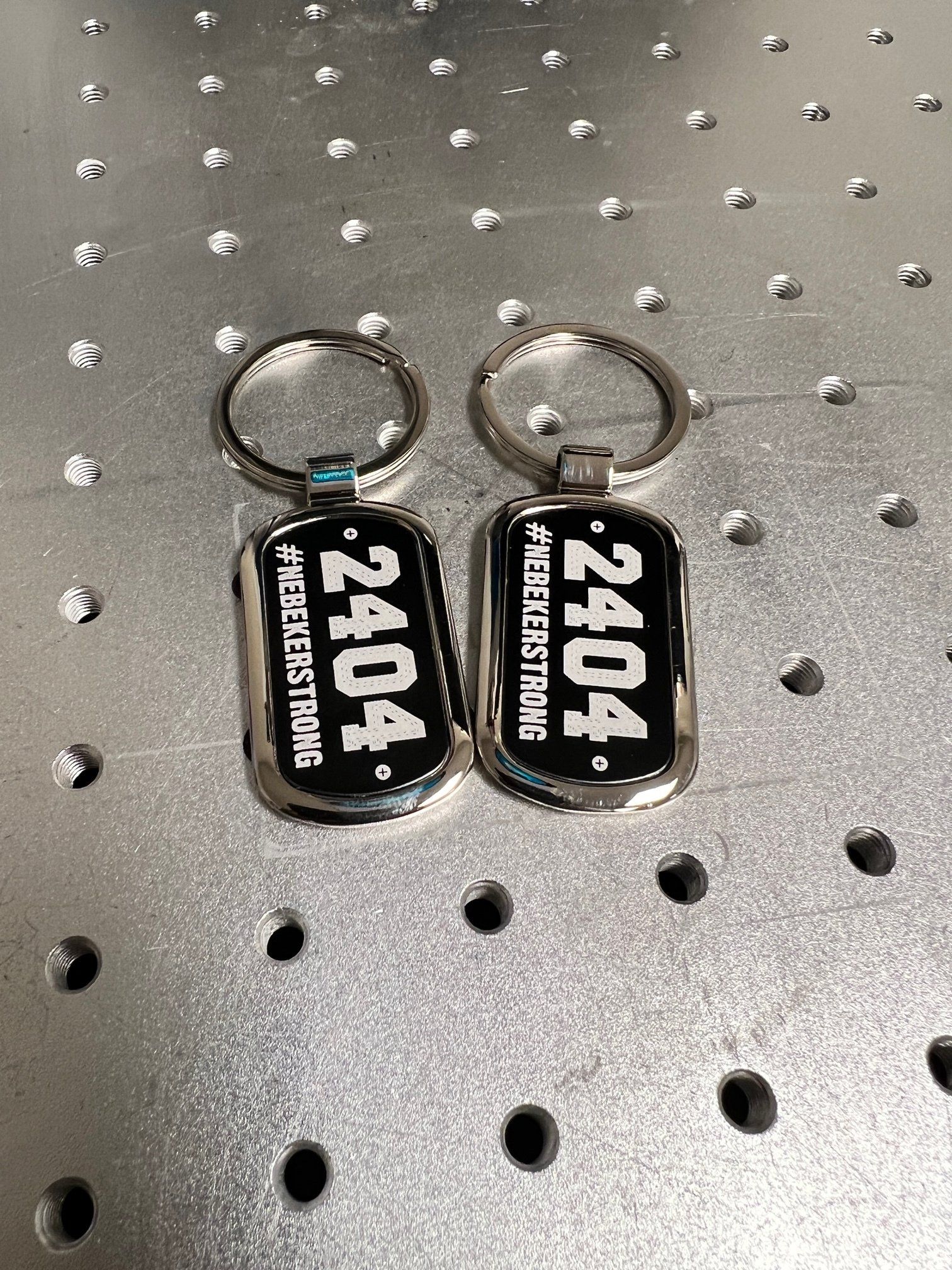 Two keychains are sitting on top of a metal surface.
