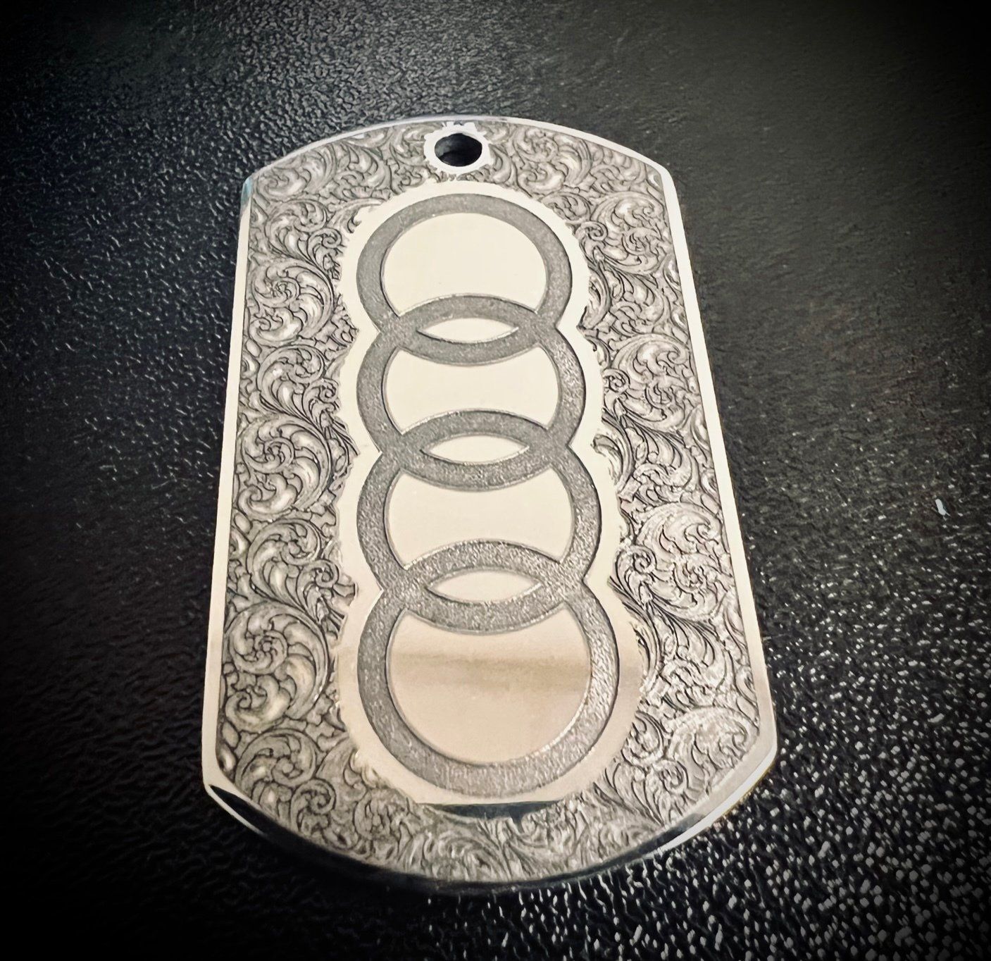 A silver dog tag with an audi logo on it