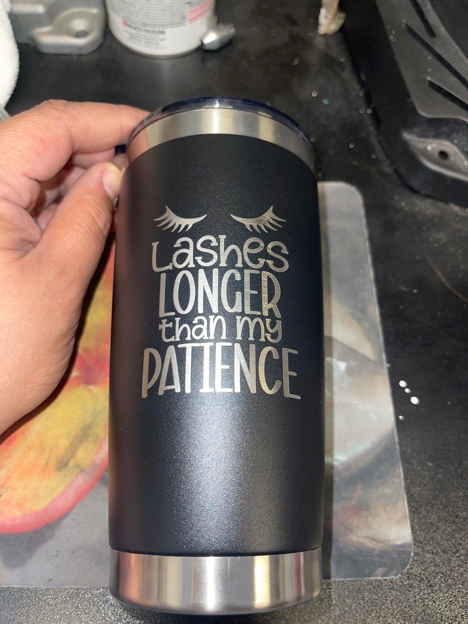 A person is holding a stainless steel tumbler that says `` lashes longer than my patience ''.