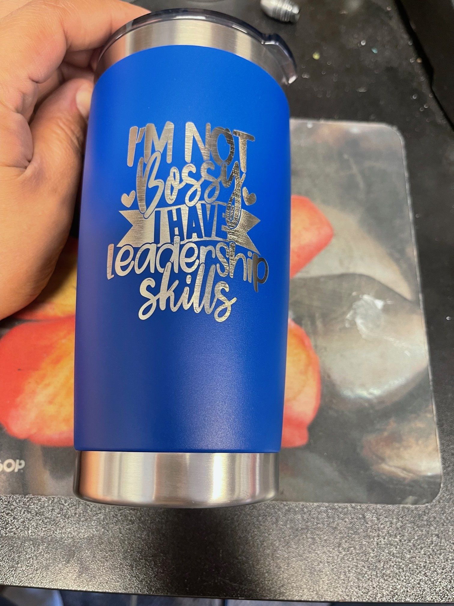 A person is holding a blue tumbler that says `` i 'm not boss , i have leadership skills ''.