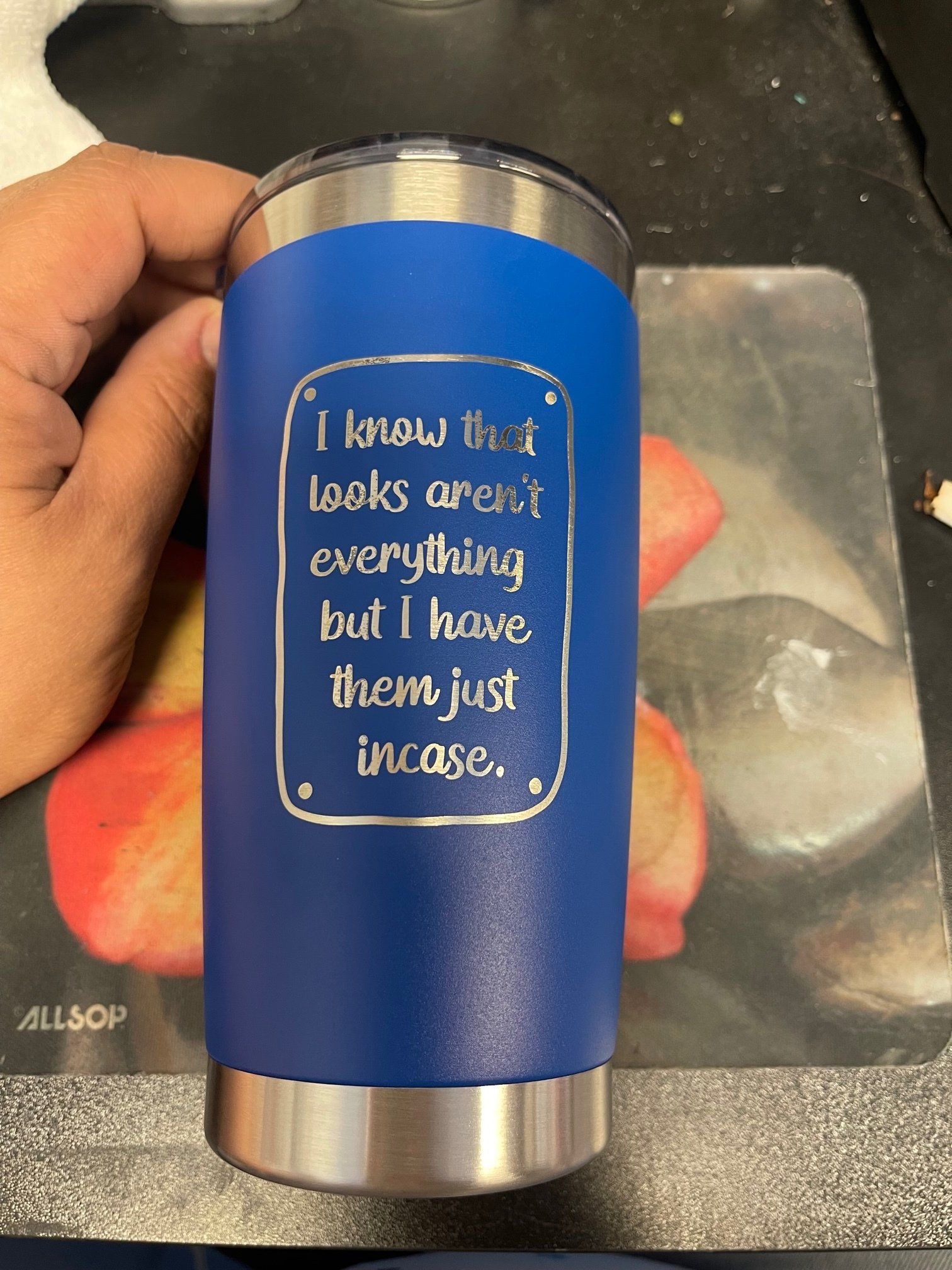 A person is holding a blue tumbler with a quote on it.