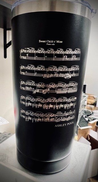 A black tumbler with a poem on it is sitting on a table.
