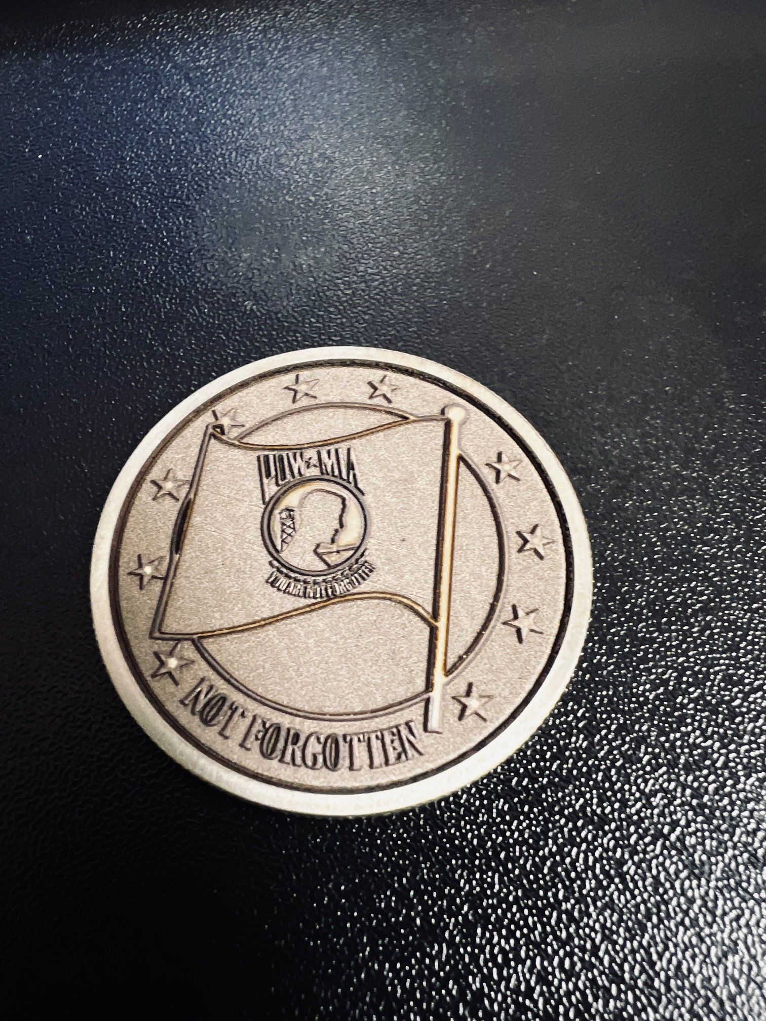 A coin with a flag on it is sitting on a black surface.