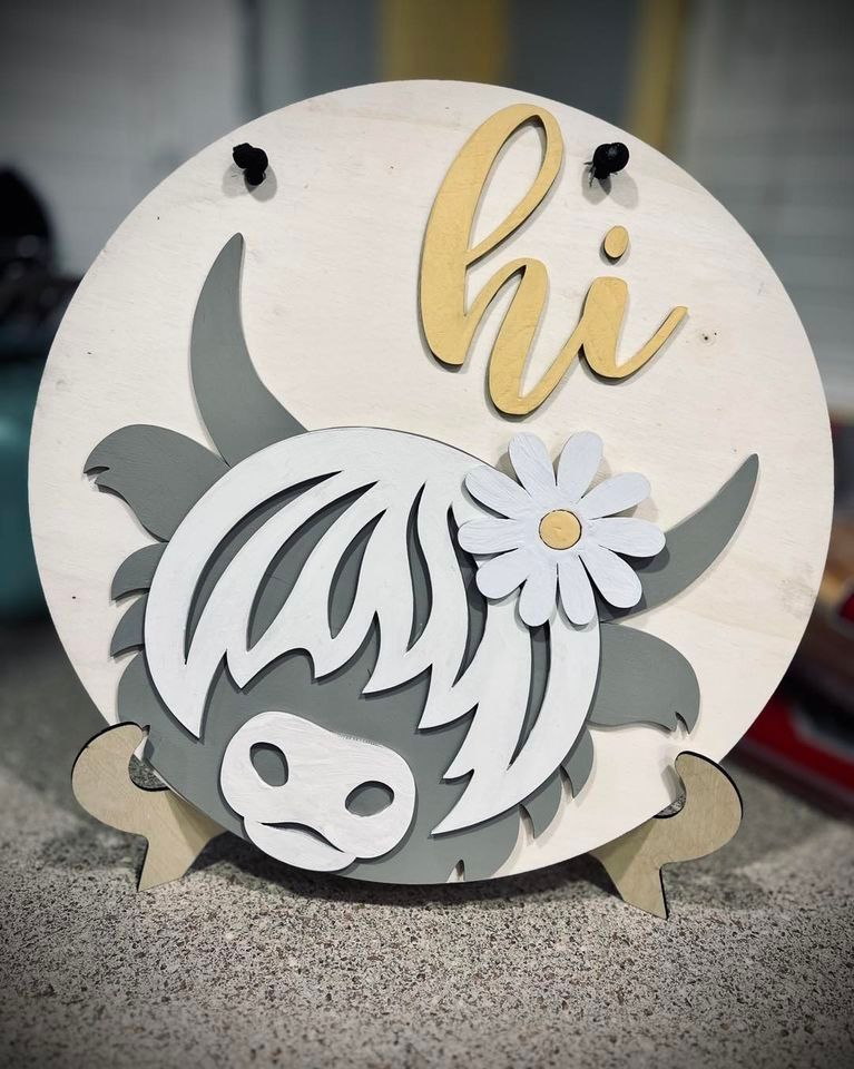 A wooden sign with a cow and a flower on it that says hi