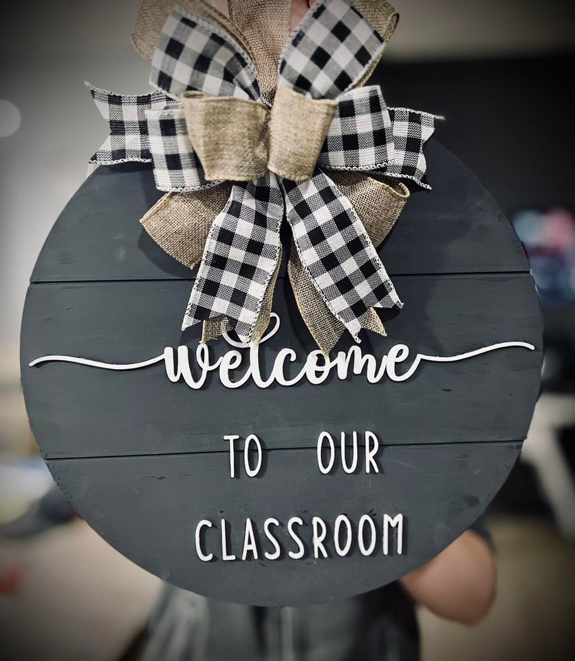 A person is holding a sign that says welcome to our classroom.