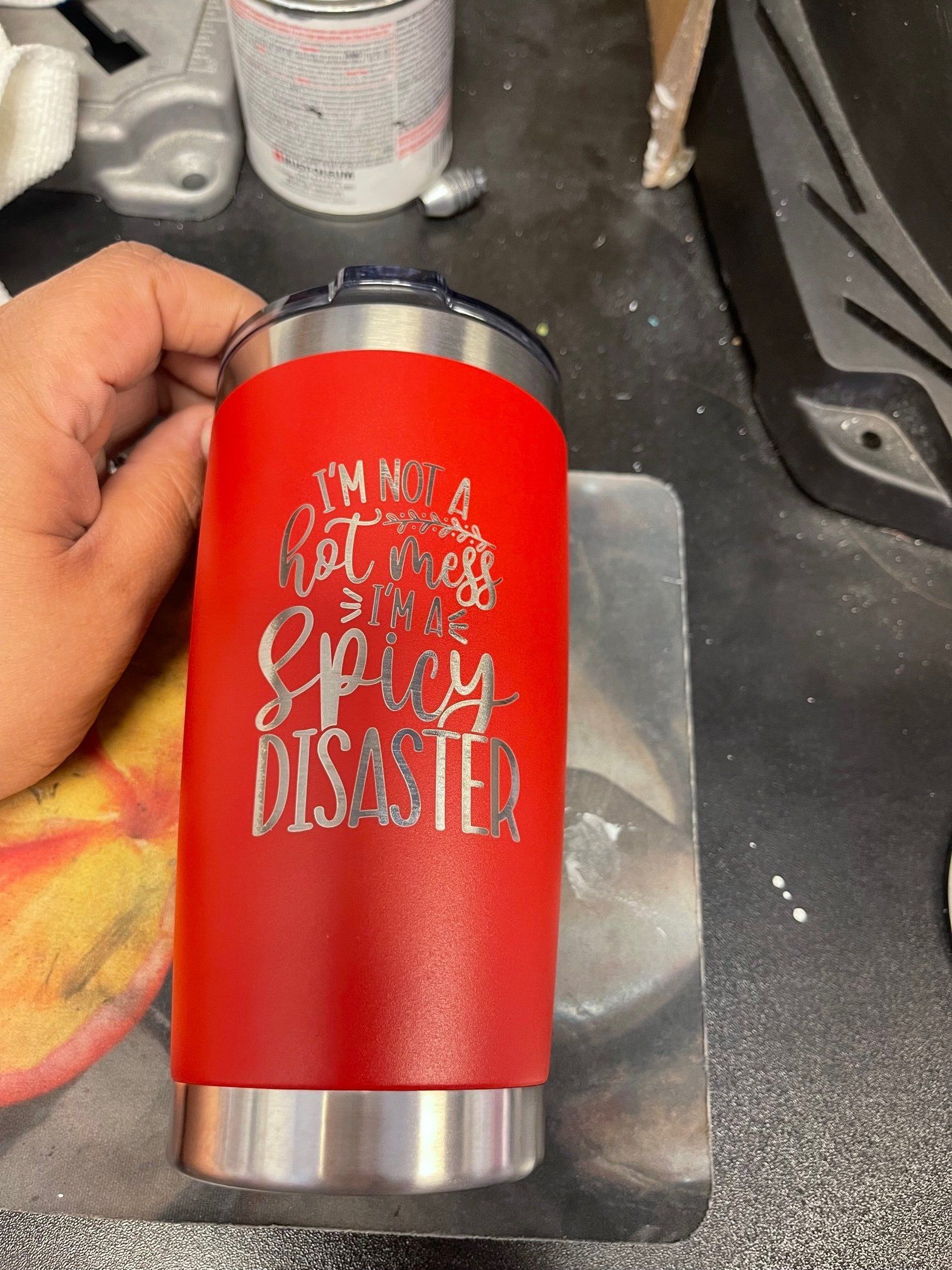 A person is holding a red stainless steel tumbler with a quote on it.