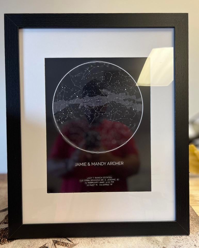 A framed picture of a starry night sky is sitting on a table.