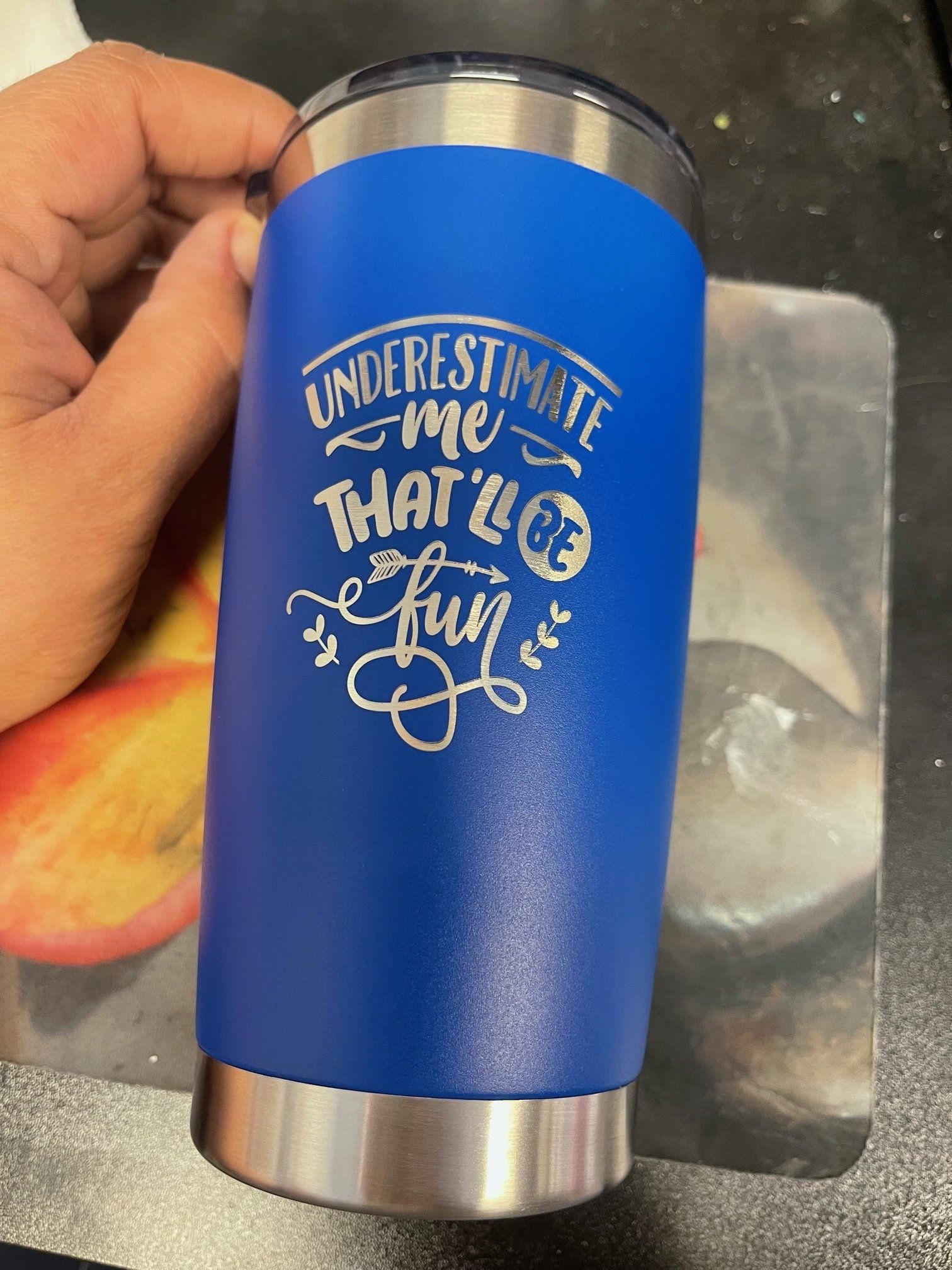 A person is holding a blue tumbler that says `` underestimate me that ll be fun ''.