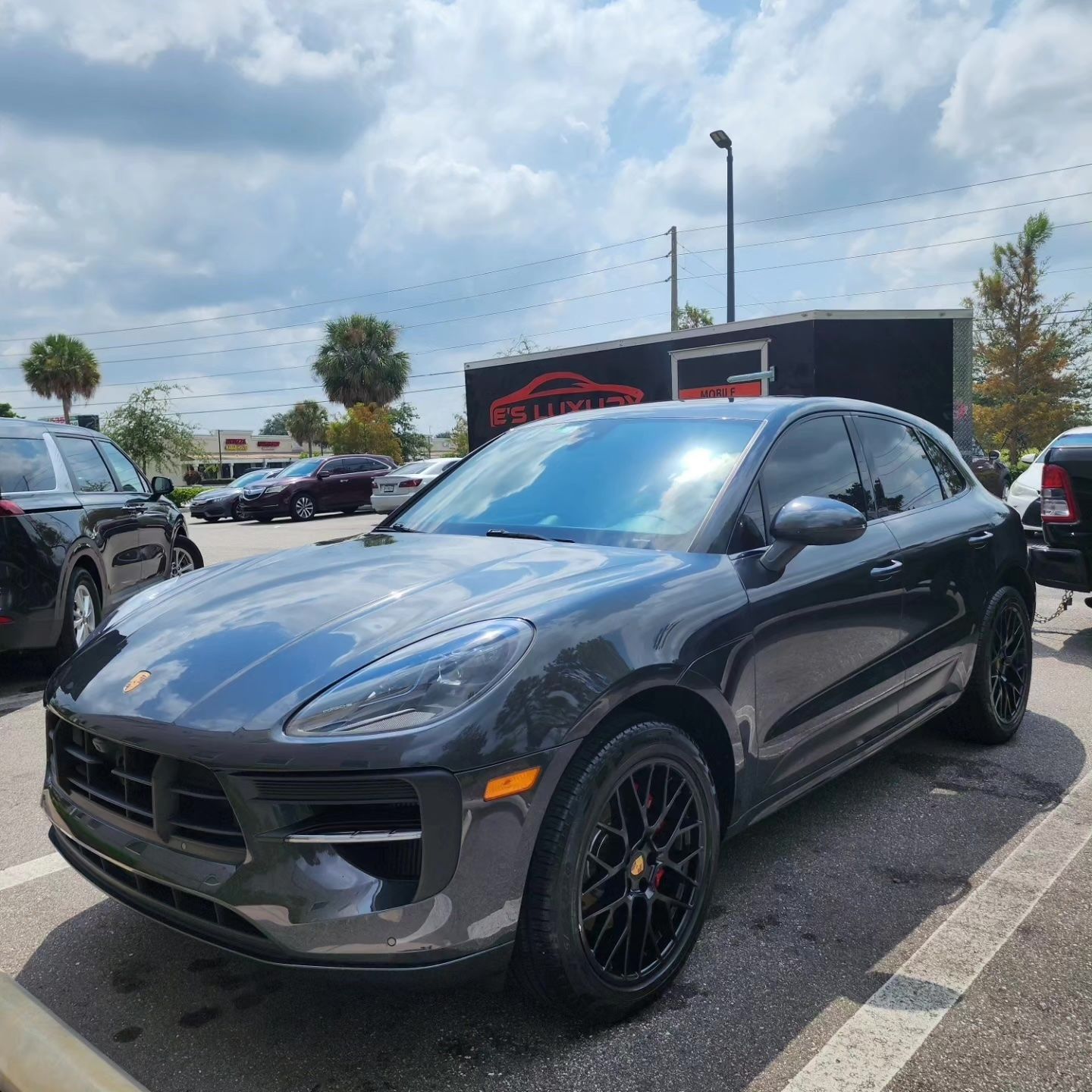 Dark gray Porsche Macan SUV parked in a lot on a sunny day.