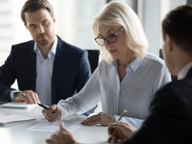 A group of business people are sitting around a table having a meeting.