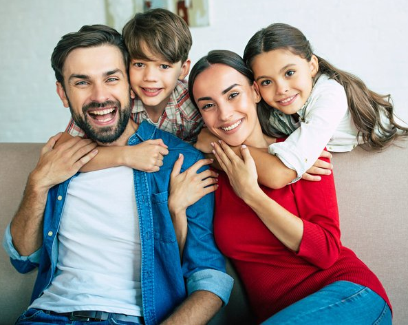 A family is posing for a picture while sitting on a couch.