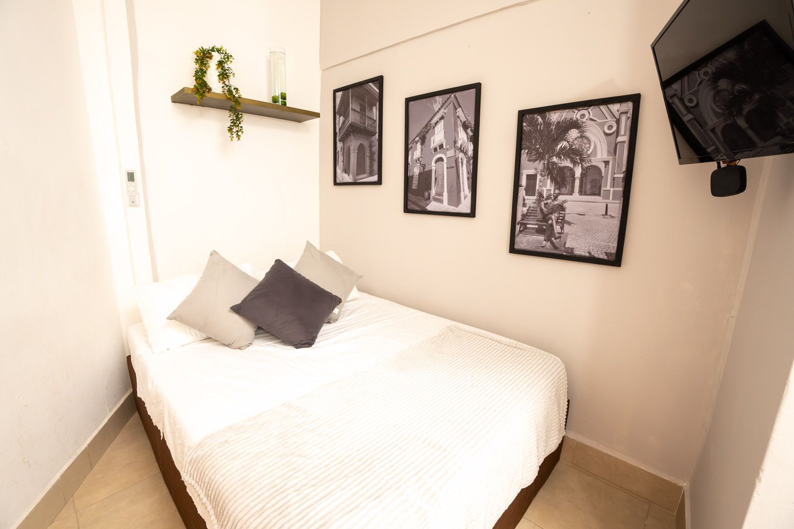 Small bedroom with exposed brick wall, bed, desk, chair, and clothes rack.