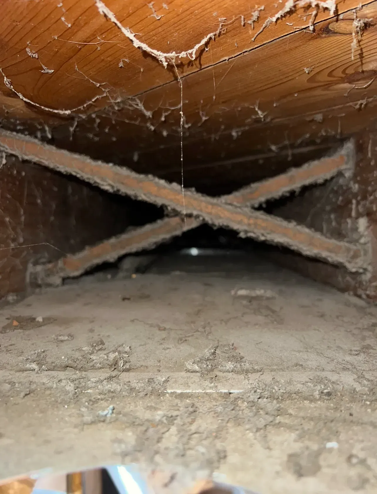 A dirty room with a wooden ceiling and a dirty floor.