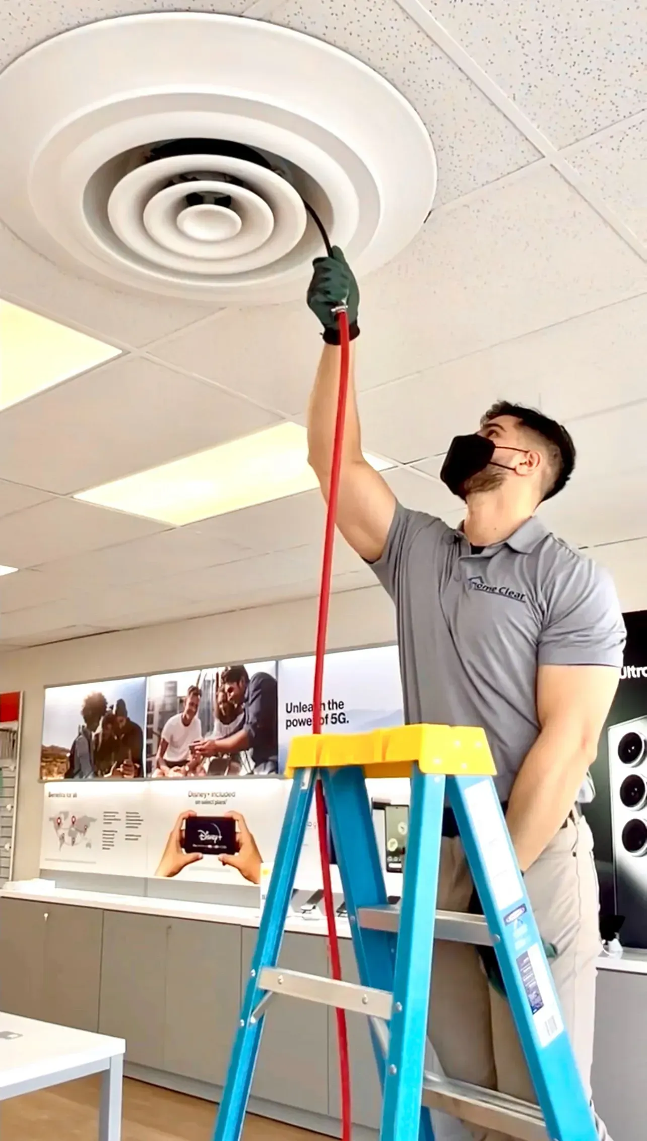 A man is standing on a ladder working on a ceiling fan.